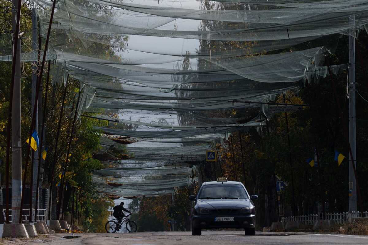 A man rides a bicycle beneath anti-drone nets over a Kherson street during the local ceasefire.