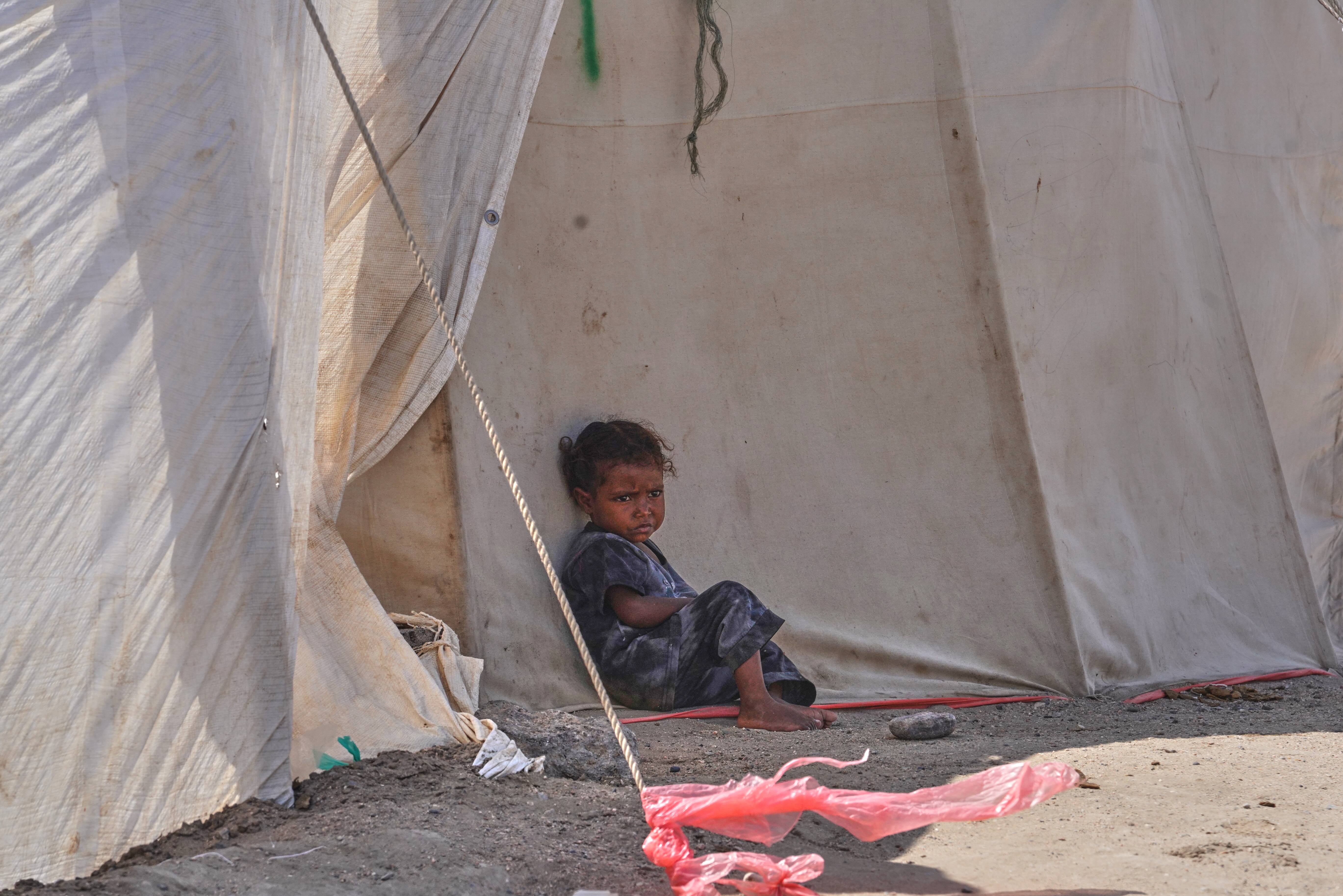 A displaced Yemeni child sits outside a tent at Al-Fardous camp near Aden.